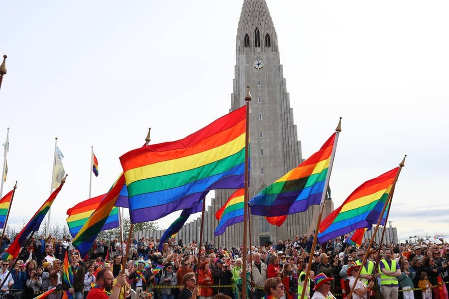 Crowd waving rainbow flags at a Pride event in front of Hallgrimskirkja church in Reykjavik, Iceland.