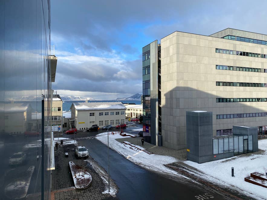 Blick auf die schneebedeckten Straßen von Reykjavik vom Storm Hotel aus. Im Hintergrund ist die Küste unter einem bewölkten Winterhimmel zu sehen.