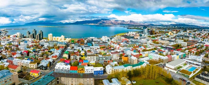 Vista aerea colorata di Reykjavik in Islanda a giugno, con cielo sereno, edifici cittadini e montagne sul mare.