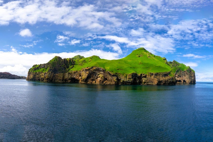 Green cliffs of a small island near Heimaey in South Iceland, part of the Westman Islands Archipelago.