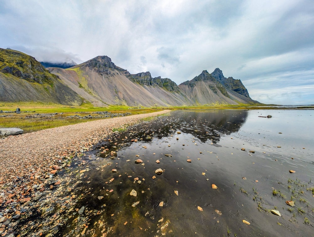 Узкая тропа ведет через покрытые травой черные песчаные дюны у подножия горы Вестрахорн в Исландии.