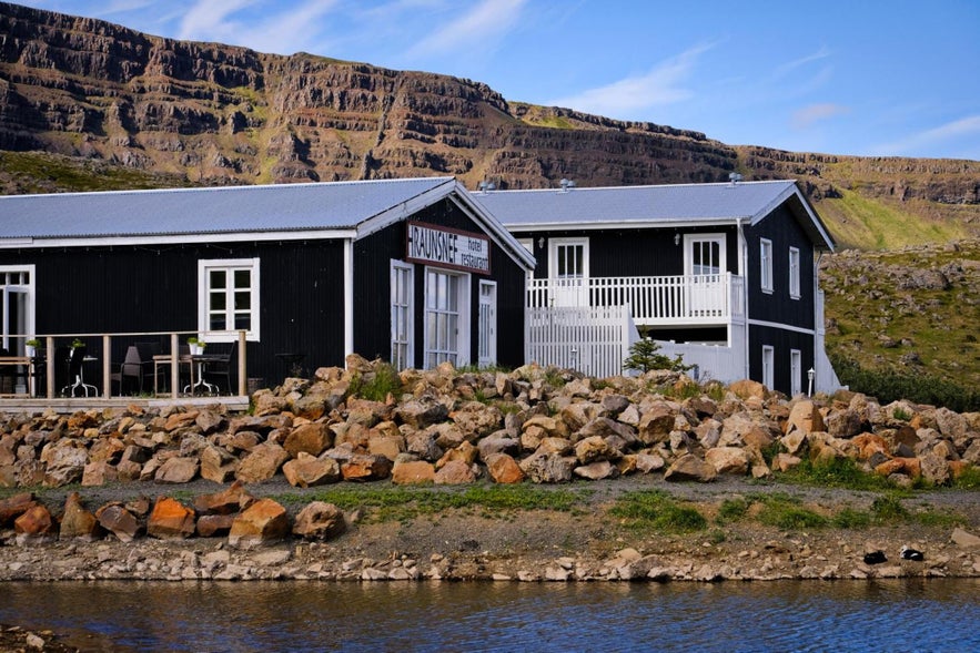 Exterior of Hraunsnef Country Hotel near Borgarnes, Iceland, with mountain backdrop and rustic stone landscaping.