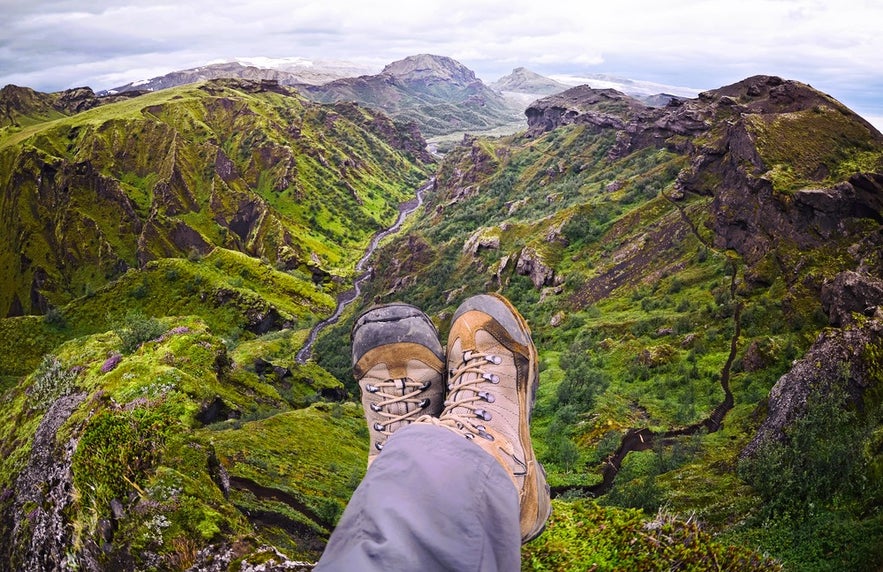 View of a green canyon in Thorsmork with hiking boots in foreground, showing one essential item of clothes and gear for Iceland tours.