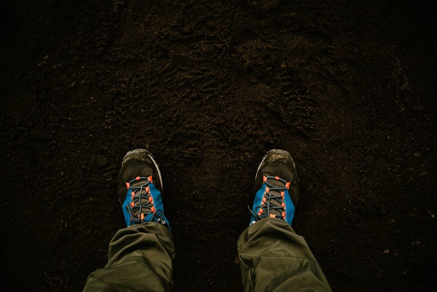 Hiking shoes on black sand at Vik Beach, showing important footwear among the clothes and gear for Iceland tours.