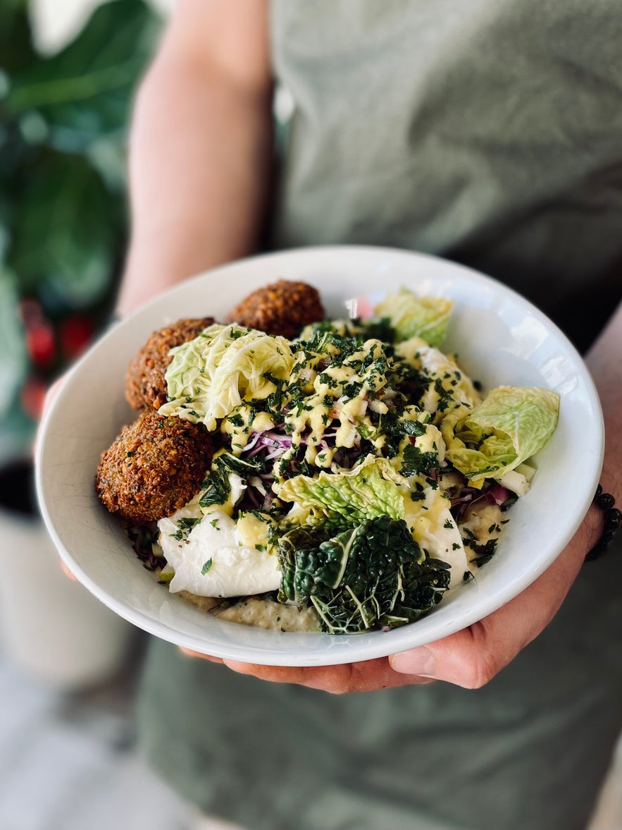 Falafel salad bowl with leafy greens and sauce served at Chikpea, a cozy vegetarian and vegan restaurant in Reykjavik.