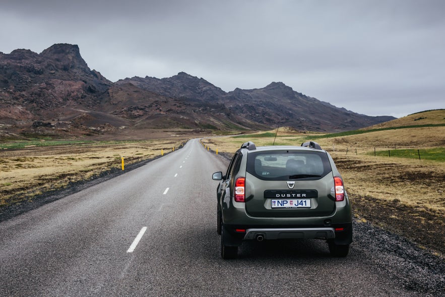 A car on a road through Reykjanes Peninsula, Iceland, where the historic Stekkjarkot turf houses are also located.