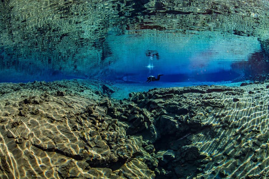 Subacqueo esplora le acque cristalline della fessura di Silfra nel Parco Nazionale di Thingvellir, Islanda.