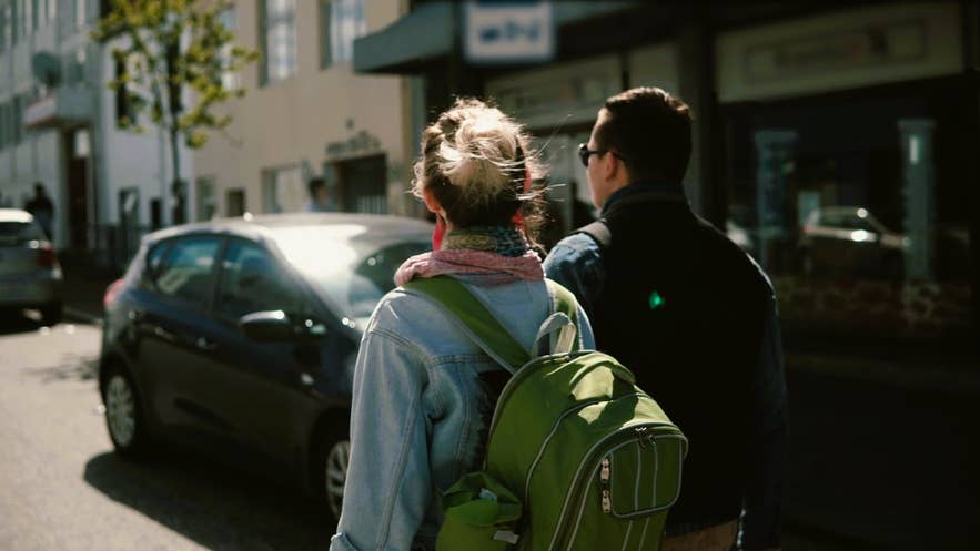 Reizigers in lichte lagen en met rugzakken in Reykjavik laten zien wat u in IJsland draagt in de zomer voor een ontspannen stadswandeling.