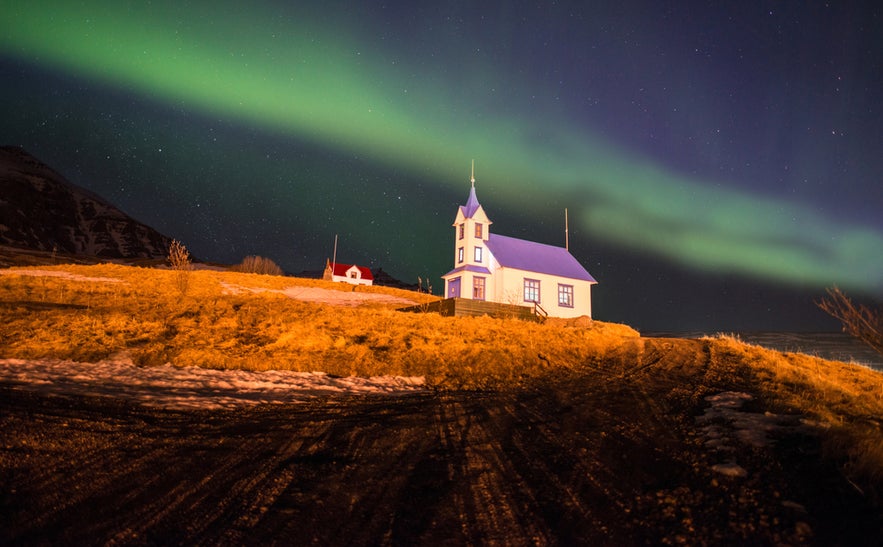 Aurora borealis glowing above a church in Stodvarfjordur, a small town in East Iceland on a clear winter night.