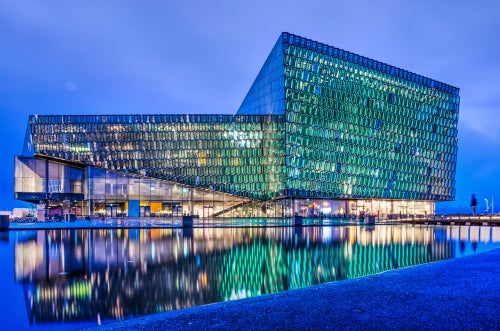 Experience the enchanting allure of Harpa Concert Hall as night falls, its illuminated facade casting a mesmerizing glow.