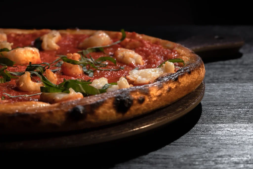 Close-up of seafood pizza with tomato sauce and herbs, served at Ishuhid Pizzeria in South Iceland.