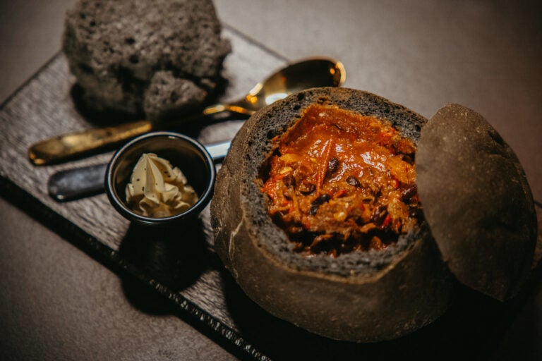 Hearty meat soup served in a black bread bowl at The Soup Company, one of the best restaurants in South Iceland.
