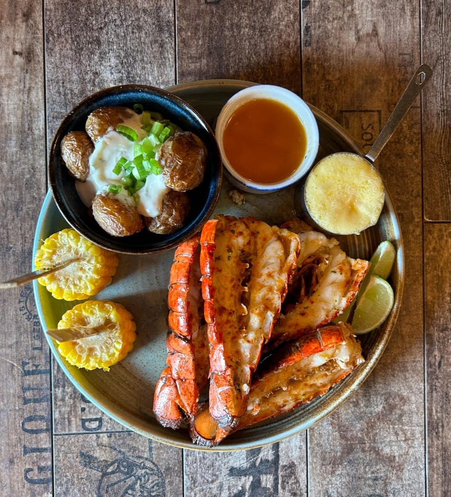 Cooked langoustine tails served with potatoes, corn, and sauce at Pakkhus Restaurant, a popular spot among Hofn restaurants.