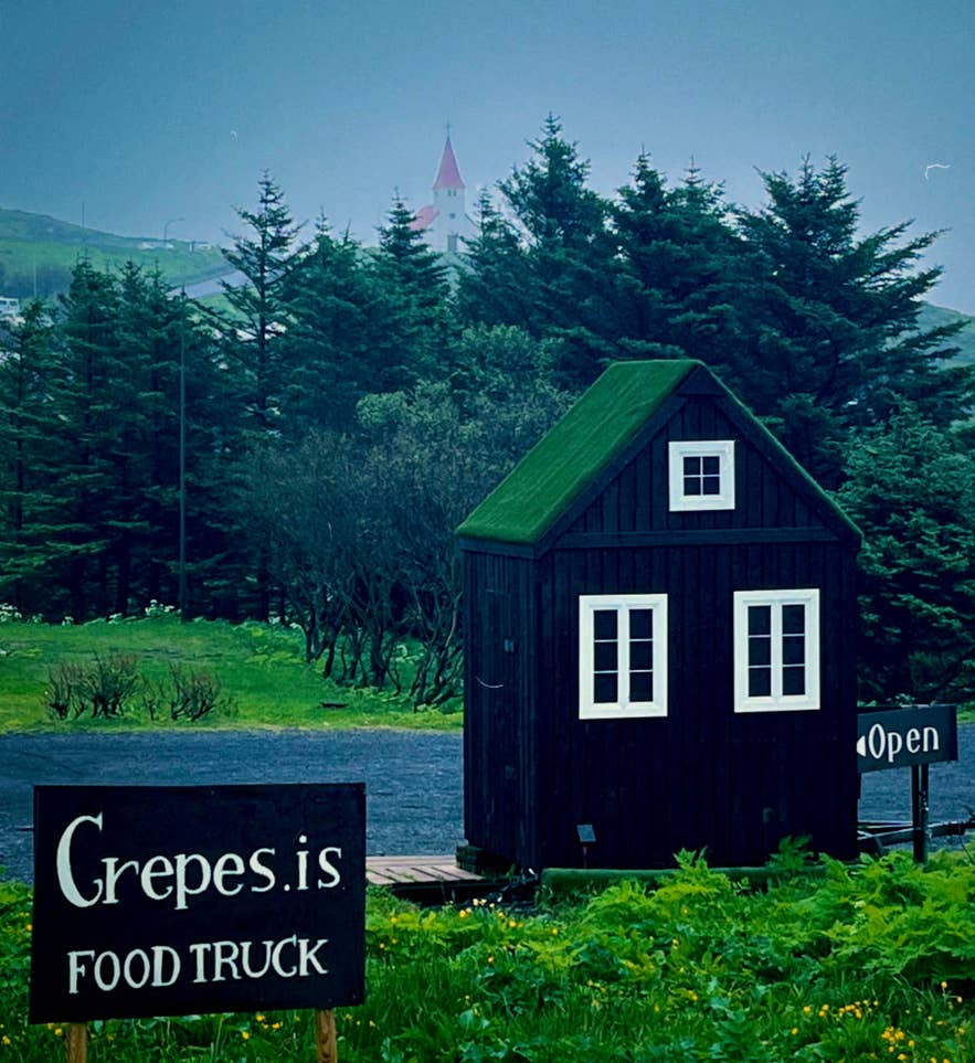 位于冰岛南部的Crepes.is餐车，坐落在一座带草皮屋顶的小黑木屋中，周围环绕着树木和乡村景致。