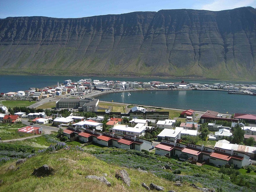Panoramic view of Isafjordur in the Westfjords of Iceland, with colorful houses, a calm harbor, and dramatic mountain cliffs.