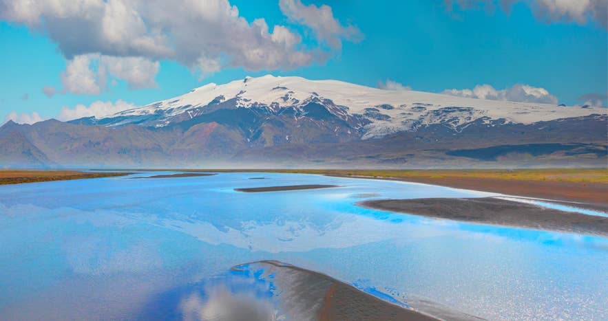 Vista panoramica del vulcano Katla sotto la calotta glaciale di Myrdalsjokull, con fiumi e cielo azzurro.