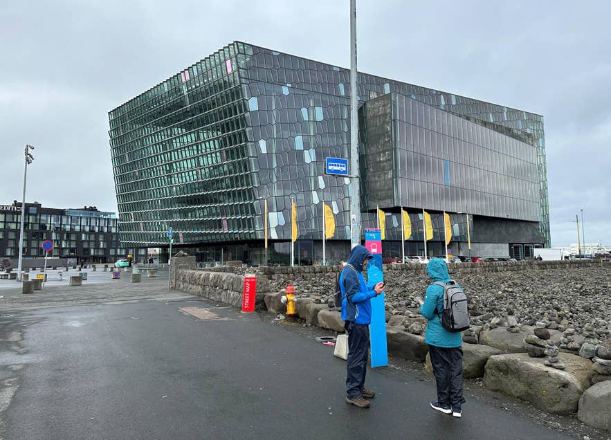 Reisende an der Bushaltestelle 5 vor der Harpa-Konzerthalle, einem beliebten Treffpunkt unter den wichtigsten Bushaltestellen in Reykjavik.