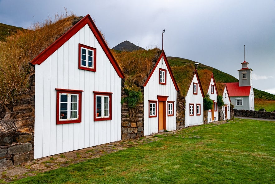 Traditional Icelandic turf houses with white wooden fronts and red trim at Laufas.