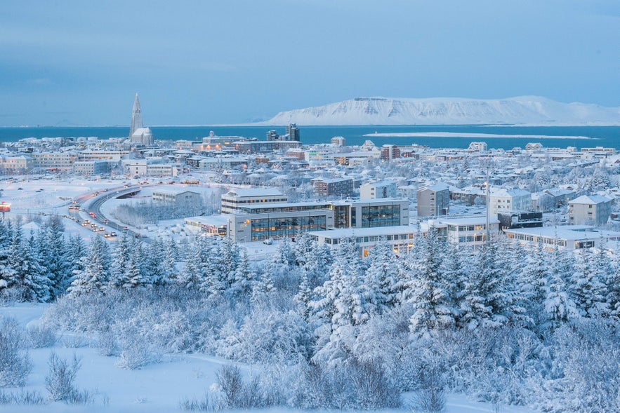 Snow-covered Reykjavik with Hallgrimskirkja Church and Esjan Mountain visible in the distance.
