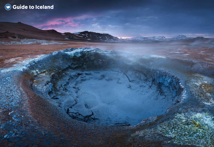 Boiling mud pool at Námaskarð geothermal area in North Iceland with colorful soil and steam rising at sunset