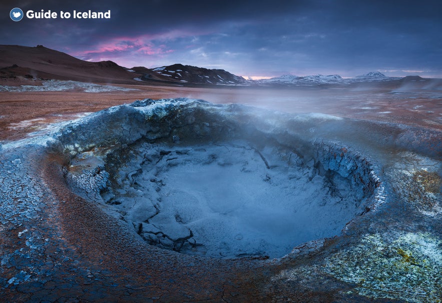 Pozza di fango bollente nell’area geotermica di Namaskard, Islanda settentrionale, con suolo colorato e vapore al tramonto