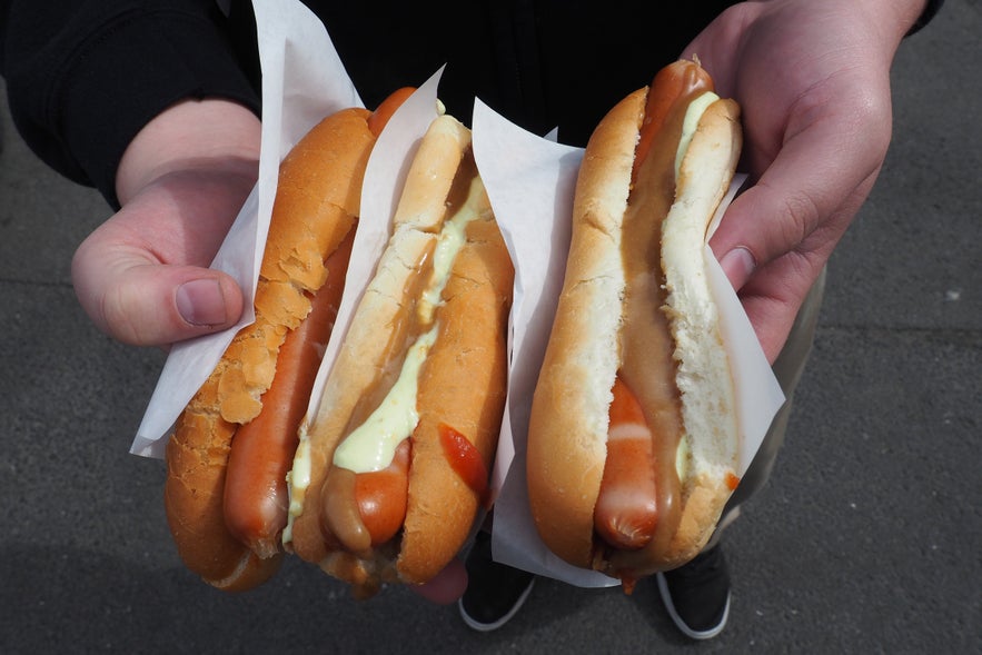 Traditional Icelandic hot dogs with lamb-based sausages, ketchup, mustard, remoulade, and crispy fried onions, served in soft buns.