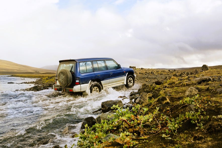 4x4 vehicle crossing a shallow river while driving in Iceland in August on remote Highland roads.