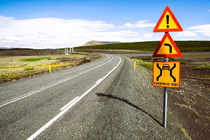 Sharp turn and narrow bridge warning signs on a Highland route in Iceland.