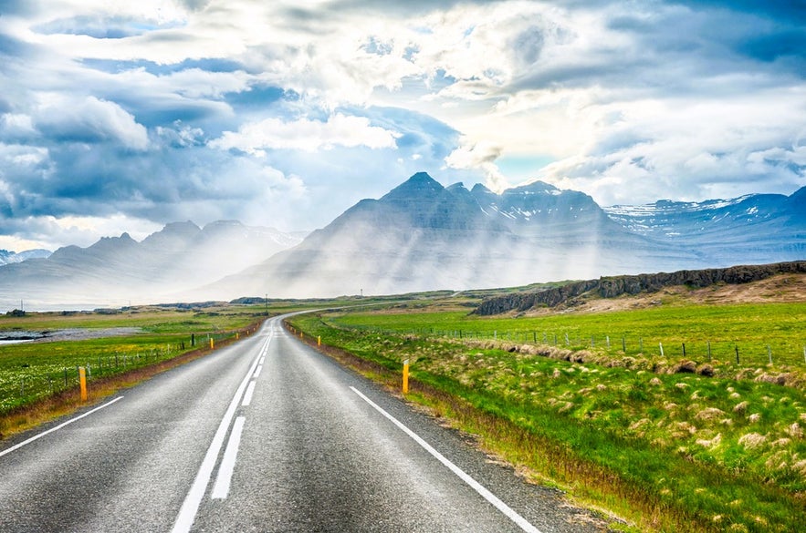 Straight paved road leading to misty mountains while driving in Iceland in August through East Iceland.
