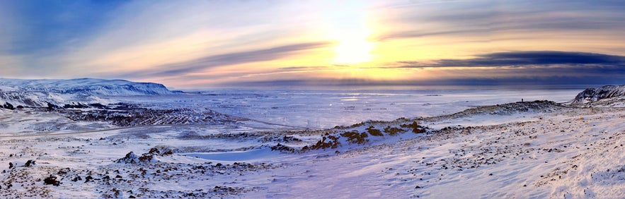 Snow-covered Blafjoll Mountains at sunset with a panoramic view of icy plains and dramatic clouds in the winter sky.