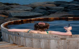 A woman enjoys a drink while enjoying a soak in a wooden tub at Musteri Spa in Blabjorg Resrort in East Iceland.