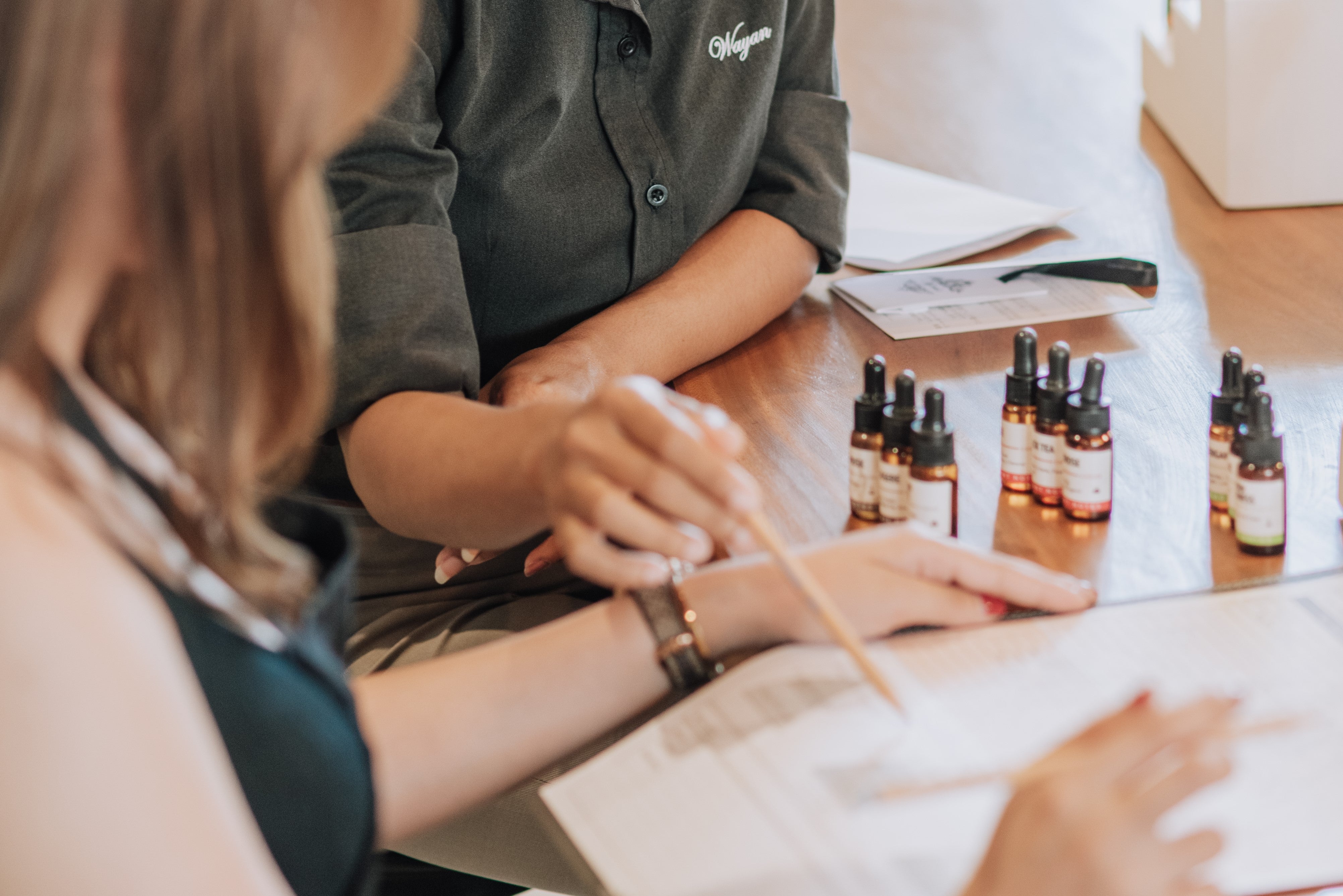 Close-up of two people discussing a scent formula during a perfume-making workshop.