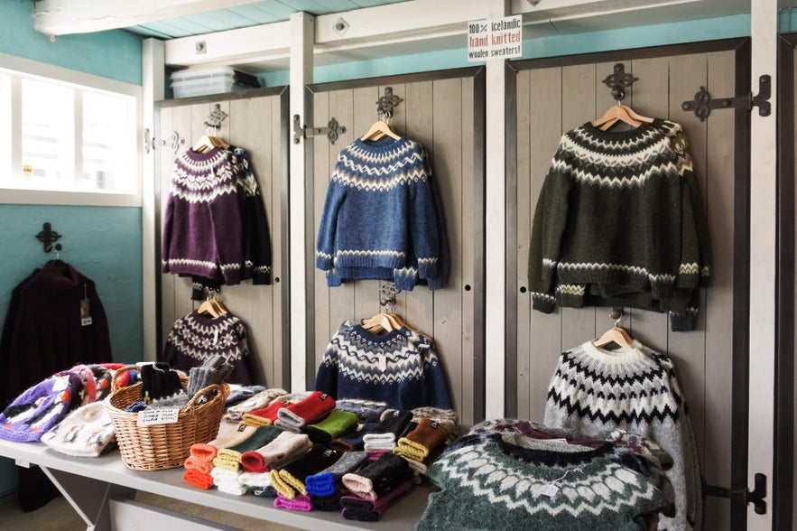 Display of colorful lopapeysa sweaters and wool accessories in an Icelandic shop featuring traditional designs.