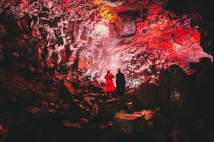 Two people enjoy the view of the interior of a lava tunnel on the Reykjanes Peninsula in Southwest Iceland.