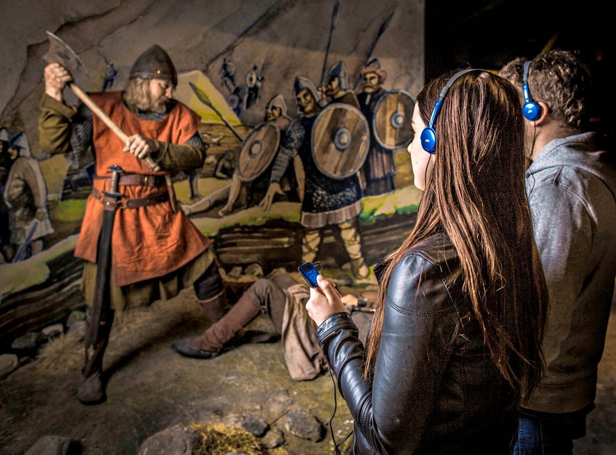 Persone che partecipano all'audio tour del Saga Museum, osservando la mostra