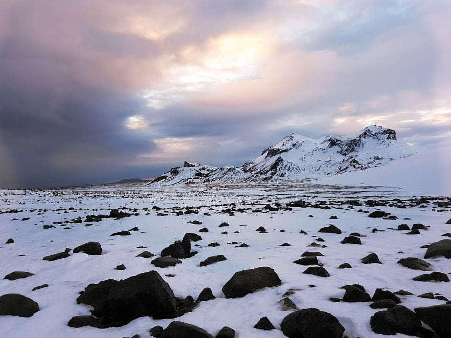 Солнечный зимний вид на ледник Лаунгйёкюдль в Исландии с ярким солнцем, отражающимся на заснеженных ландшафтах.