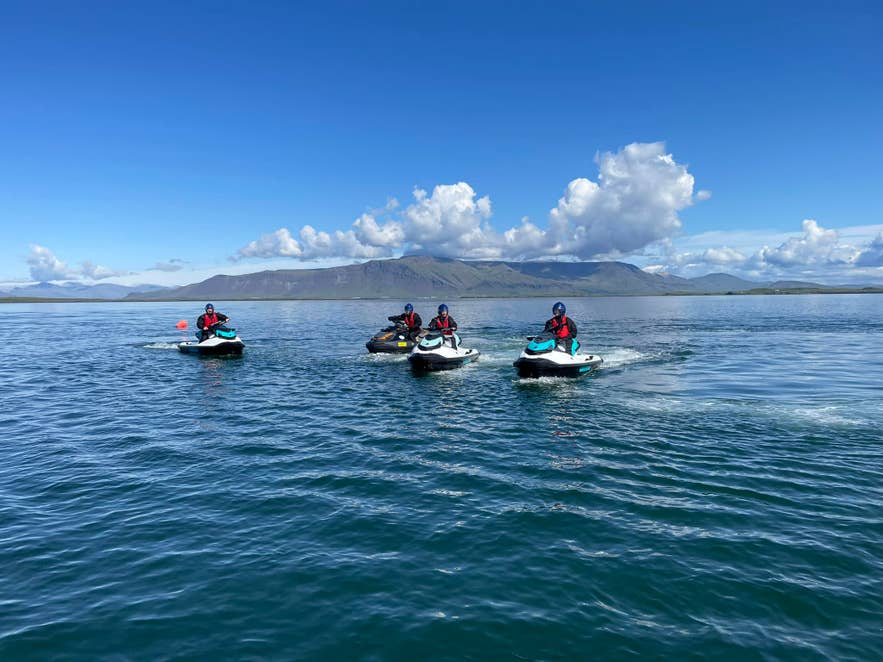 Jet ski riding across Faxafloi Bay near Reykjavik with coastal views in the background.