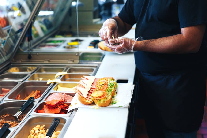 A sandwich shop staff prepares sandwiches