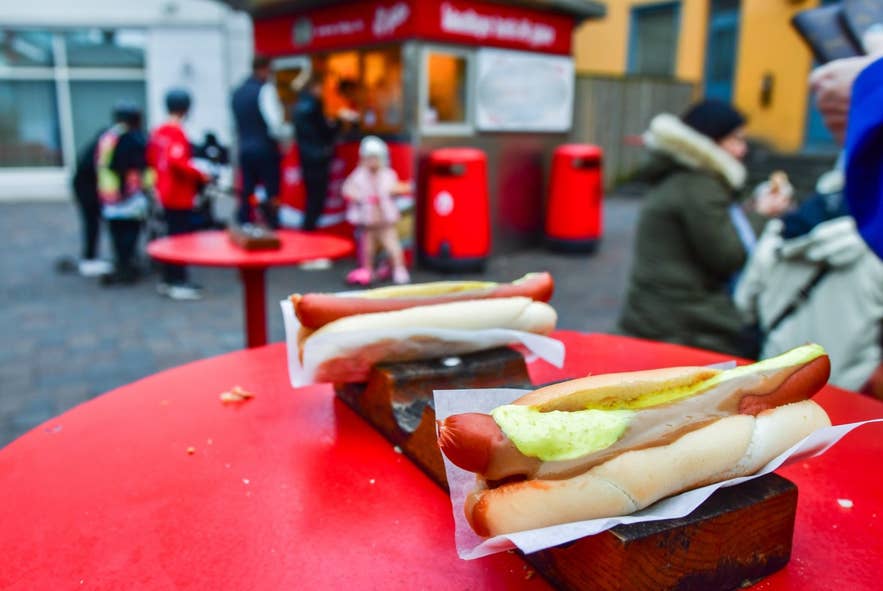 Close up of traditional tasty hotdogs and customers standing in line