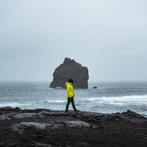 A person walking on the volcanic coastline of the Reykjanes Peninsula.