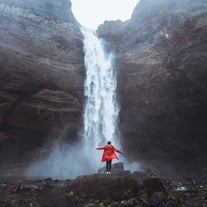 A person stands at the bottom of Haifoss waterfall, one of the tallest waterfalls in Iceland.