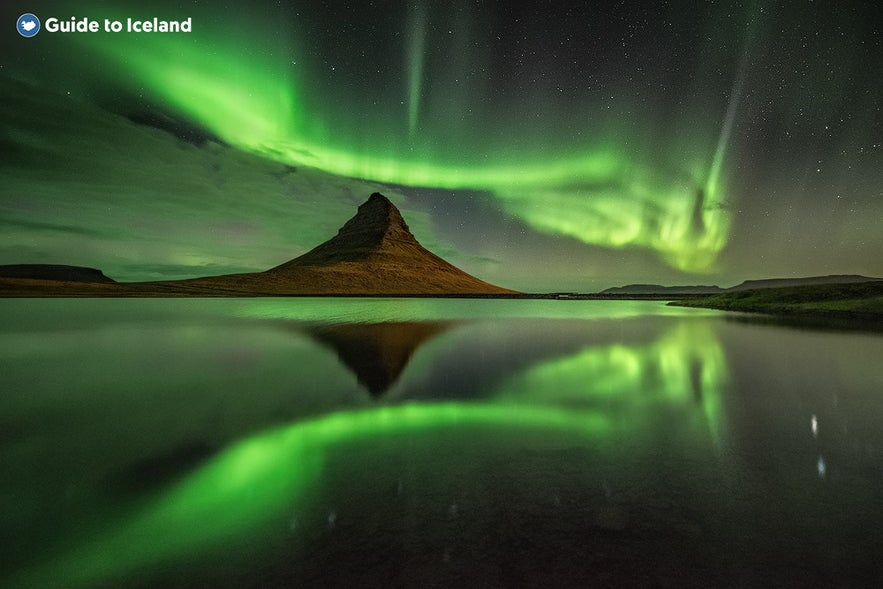 Die Nordlichter spiegeln sich perfekt im Meer unter dem Berg Kirkjufell.