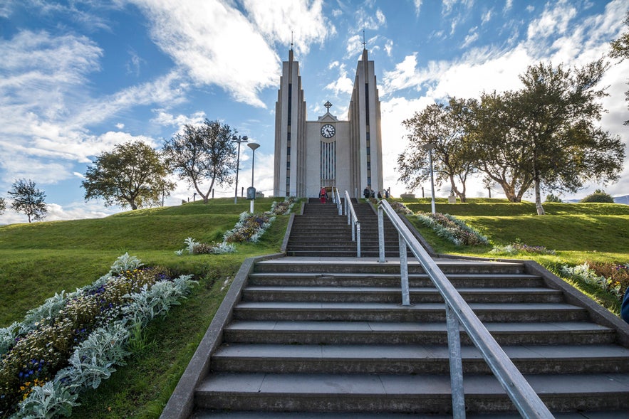 Steps leading to Akureyrarkirkja (Akureyri Church) in Akureyri under a blue sky with scattered clouds. Steps leading to Akureyrarkirkja (Akureyri Church) in Akureyri under a blue sky with scattered clouds.