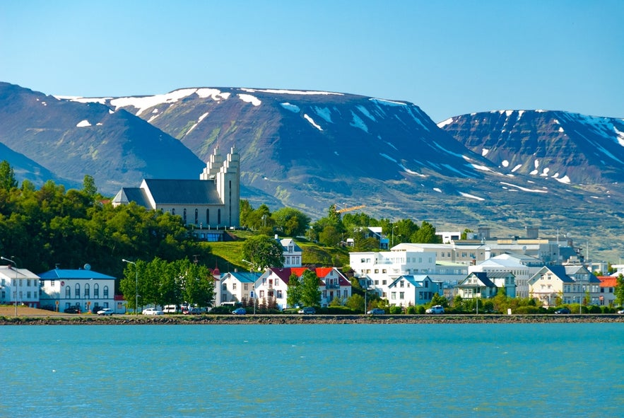 View of Akureyri with Akureyrarkirkja church and snow-streaked mountains in the background across the fjord.