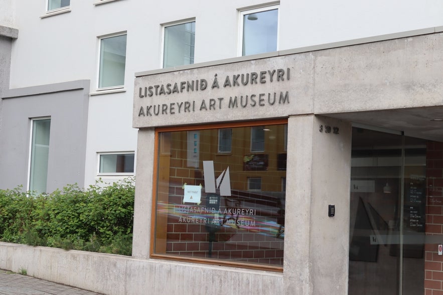Entrance of the Akureyri Art Museum with signage in Icelandic and English, set in a modern concrete building.