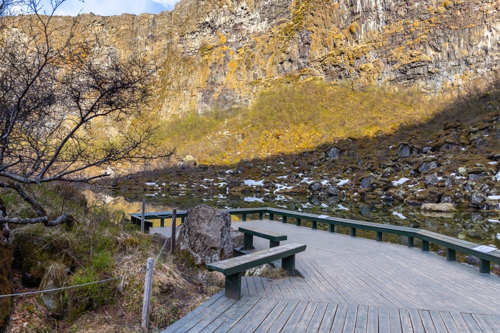 Asbyrgi Canyon in North Iceland features a wooden platform at Botnstjorn Lake, as well as cliffs and mossy rocks.