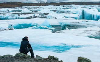 A traveler enjoys the floating icebers at Jokulsarlon Glacier Lagoon on a private South Coast tour from Reykjavik.