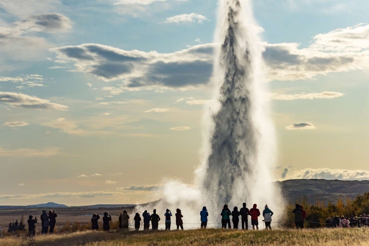 Travelers admiring the erupting Strokkur Geyser in Geysir Geothermal Area during a Golden Circle tour.
