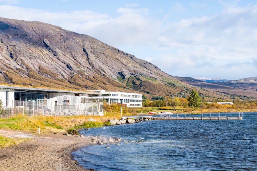 Shore of Laugarvatn in Iceland, with a dock, calm lake waters, and scenic mountains in the background.