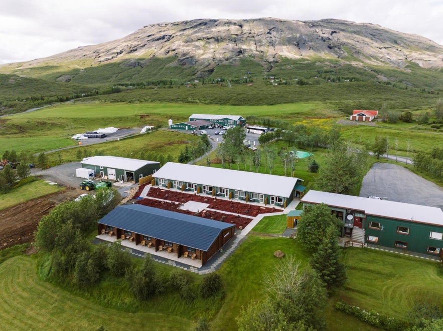 Aerial view of Efstidalur Farm Hotel along Iceland’s Golden Circle, set in lush fields with mountains in the background.